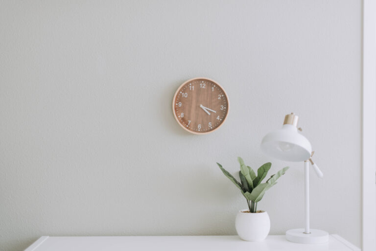 plant and lamp on table with clock on wall