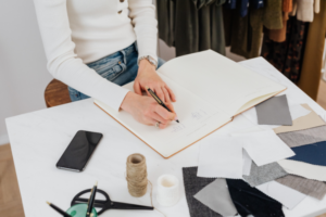 woman sitting at desk with notebook and fabric samples