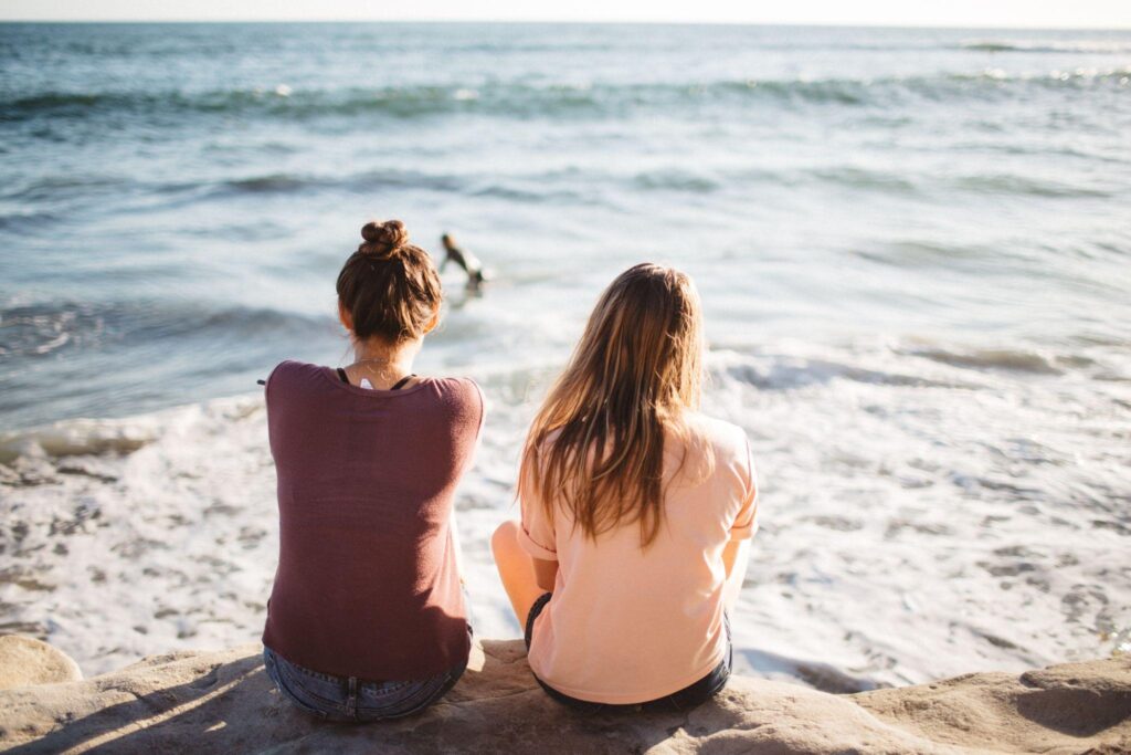 2 women sitting on the beach