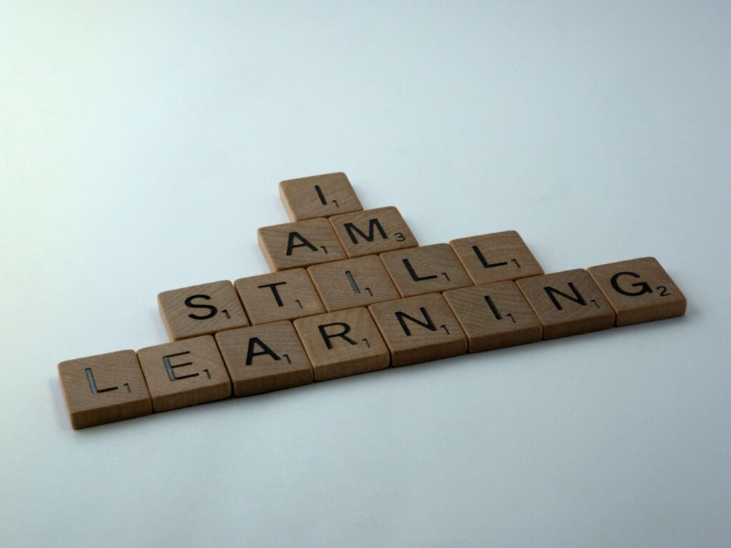 scrabble tiles spelling out "I am still learning"