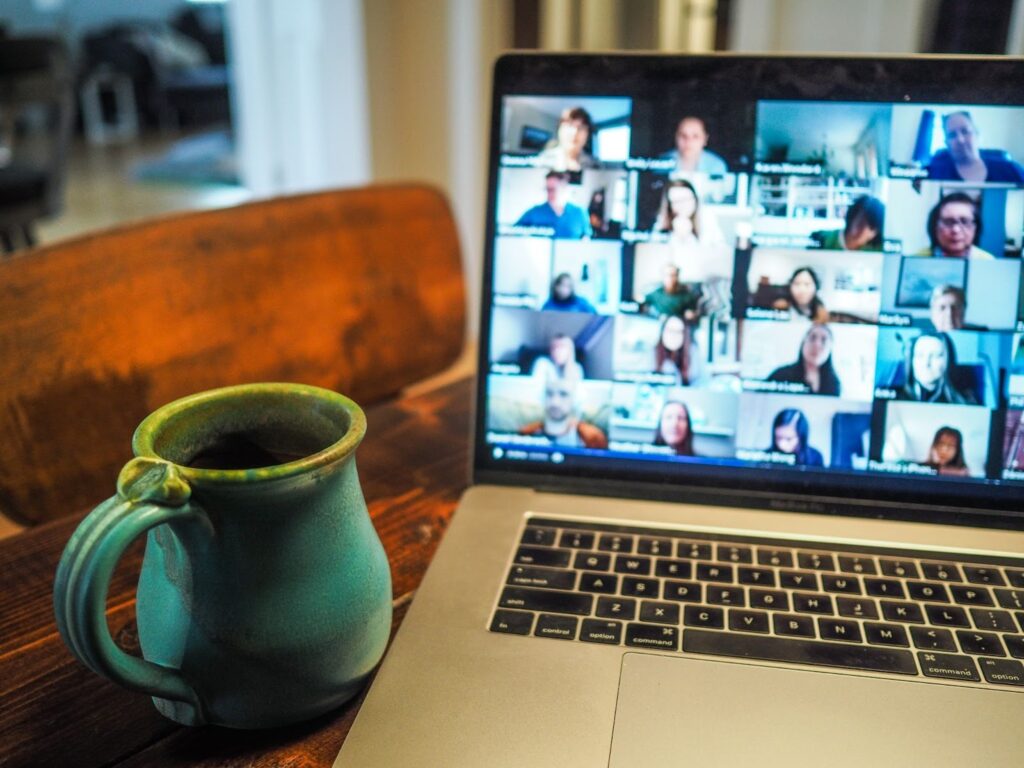 laptop computer with a networking call on the screen. green coffee cup next to the computer