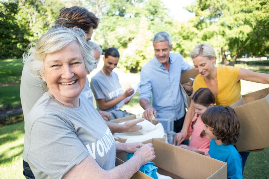 group of volunteers packing boxes. older woman facing the camera and smiling in the foreground