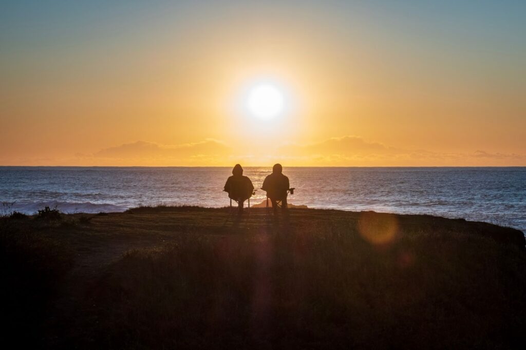 couple sitting on the beach at sunset