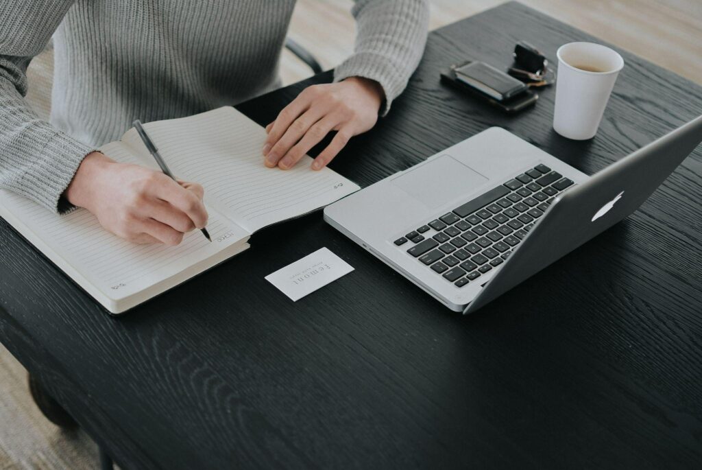 person working at a laptop with journal and coffee