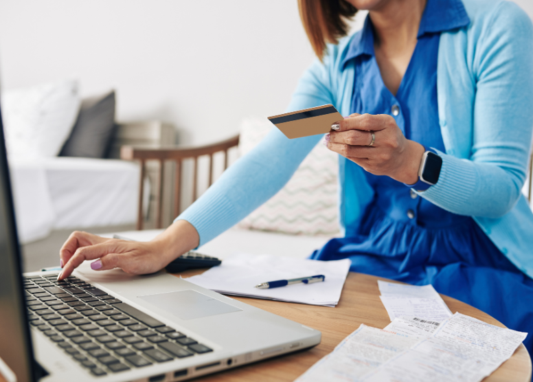 woman holding a credit card and typing on a laptop computer