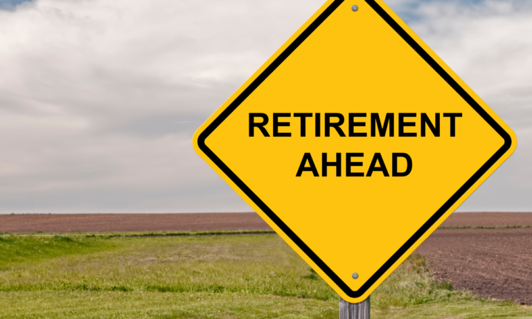 yellow diamond-shaped road sign with "Retirement Ahead" in black letters. Sign is out in a field