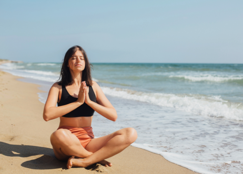 woman doing yoga on the beach near the water