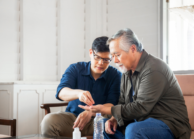 younger man giving an older man medication