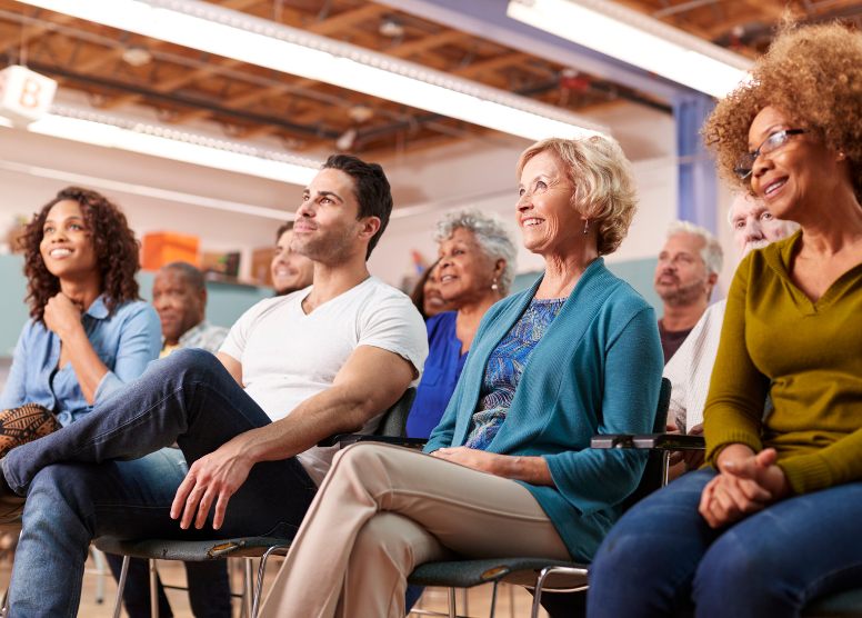 group of people sitting in chars in a large room looking and listening to someone out of camera view in front of them