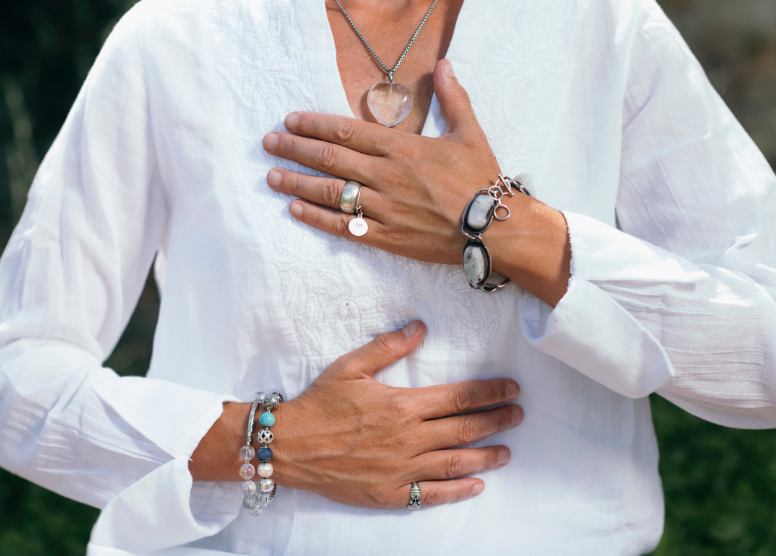 torso view of a woman; right hand is on her stomach and left hand is on her chest