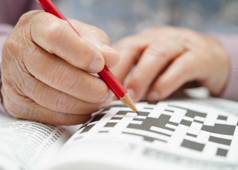 close up of person's hands working a crossword puzzle