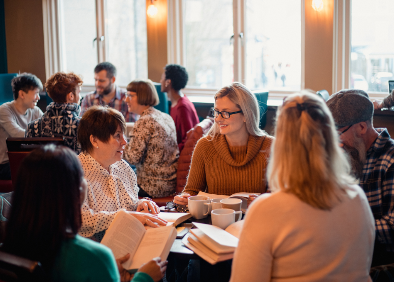 groups of people sitting at tables in a coffee shop having a book club meeting