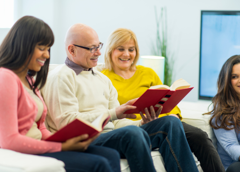 group of people sitting on a sofa reading together