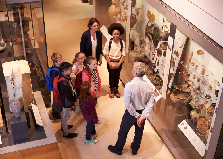 male museum guide giving a tour to a small group of children