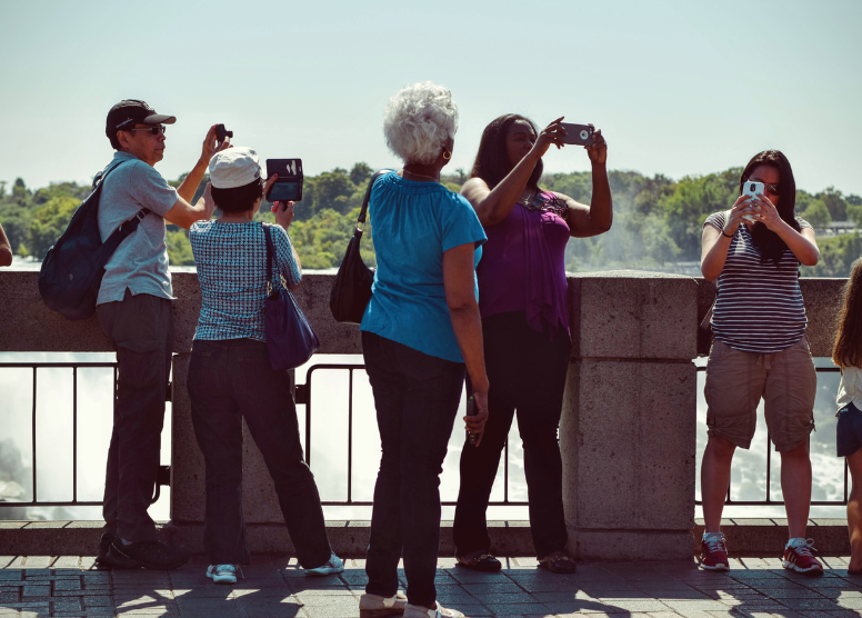 group of tourists standing and taking pictures on a bridge over a river or waterfall