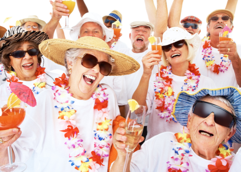 group of seniors dressed in beach shirts, hats, leis, sunglasses. Holding champagne flutes and cocktail glasses