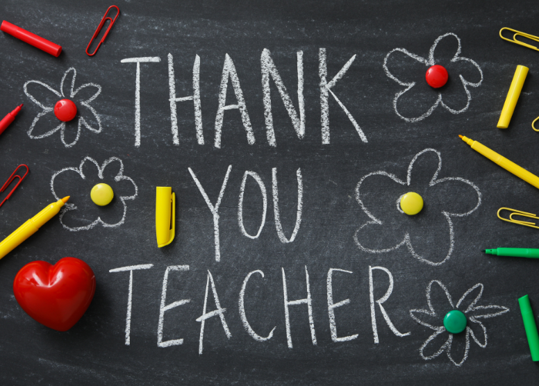 chalkboard with "Thank you teacher" written in white chalk, flowers drawn in white chalk with colored button centers, red heart, colored markers and paperclips