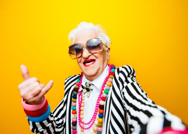 older woman in wild clothes and big square sunglasses taking a selfie