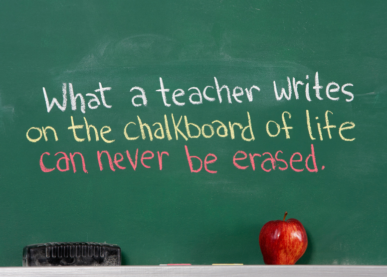 green chalkboard with the words "What a teacher writes on the chalkboard of life can never be erased." Eraser and apple sitting on chalk holder