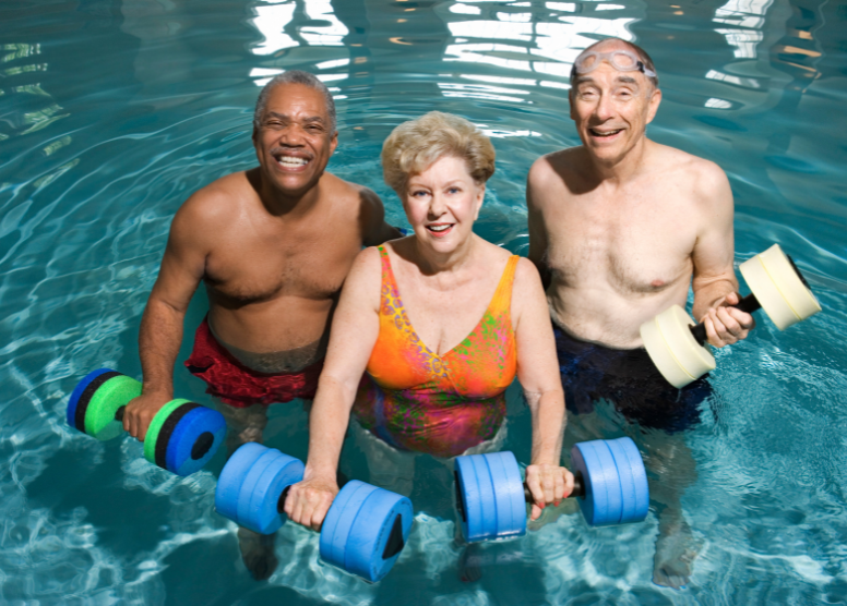 three older people in a pool, holding water weights