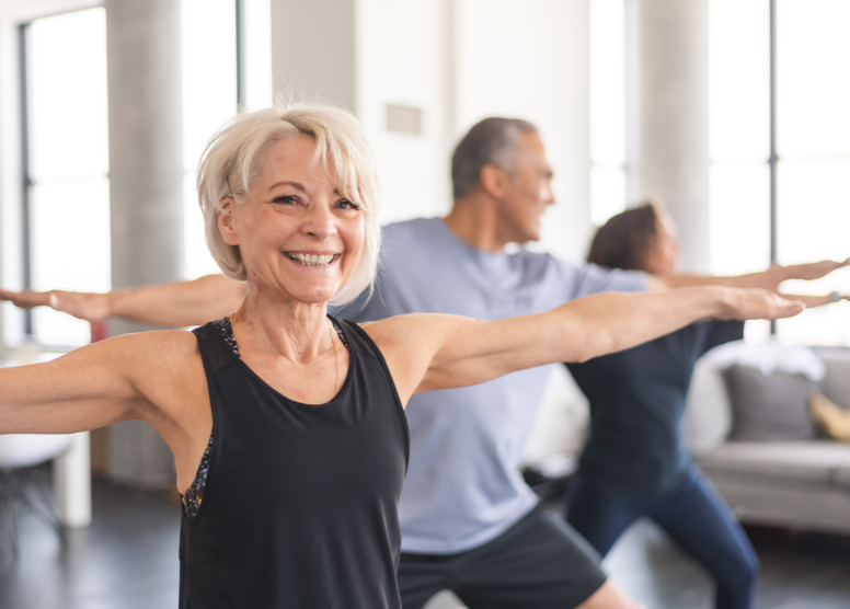 retirees doing yoga. Woman in front is facing the camera and smiling