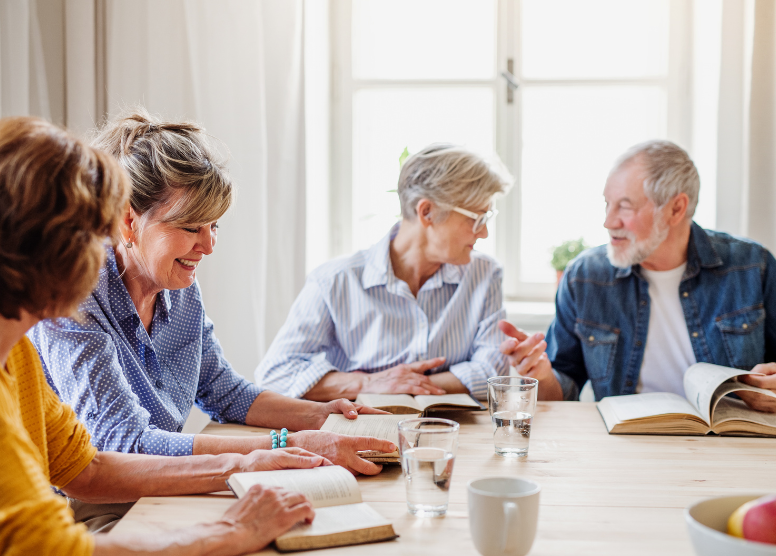 group of seniors seated around a table reading and discussing