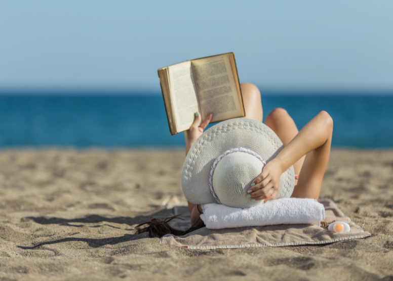 woman lying on the beach reading a book