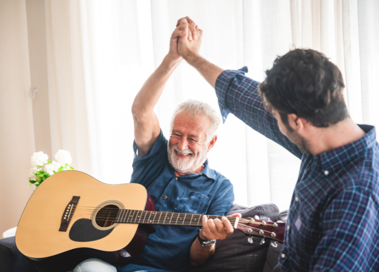 older man holding a guitar and giving a younger man a high-five