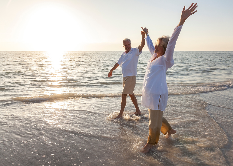 older couple calking in the shallow water on the beach