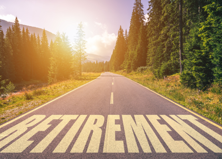 road with tall trees on either side. Word "Retirement painted on the road in the foreground of the image