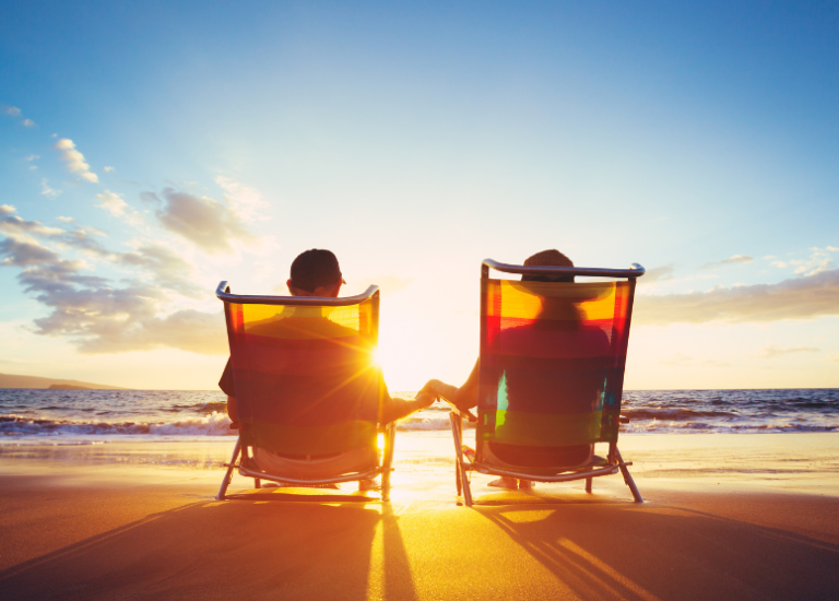 back view of couple sitting in beach chairs on the beach at sunset