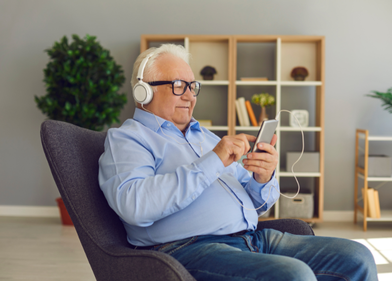 older man sitting in a chair listening to podcasts for seniors